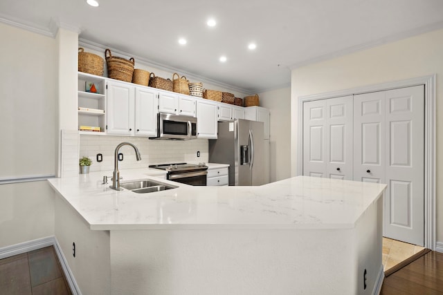 kitchen featuring sink, stainless steel appliances, kitchen peninsula, white cabinets, and ornamental molding