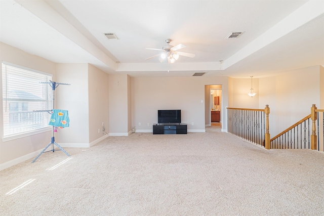 unfurnished living room with light colored carpet, a raised ceiling, and ceiling fan