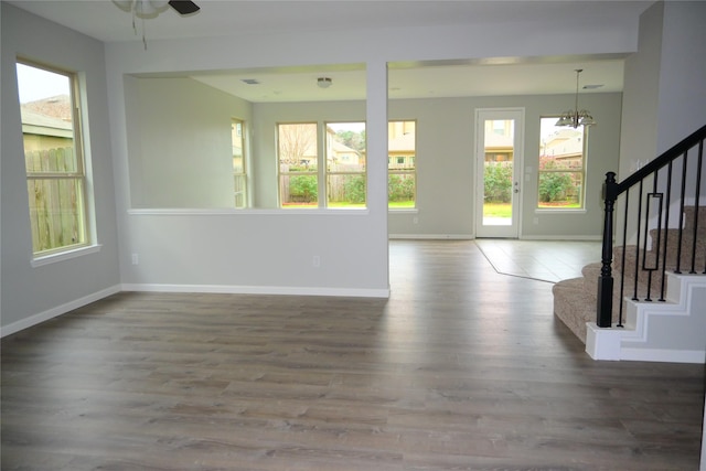 interior space featuring ceiling fan with notable chandelier and dark hardwood / wood-style flooring