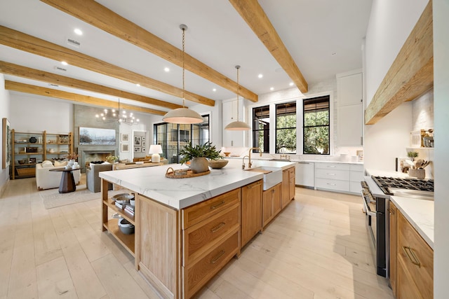 kitchen featuring white cabinetry, stainless steel range, decorative light fixtures, and a spacious island