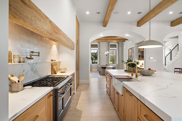 kitchen featuring high end range, tasteful backsplash, sink, beam ceiling, and pendant lighting