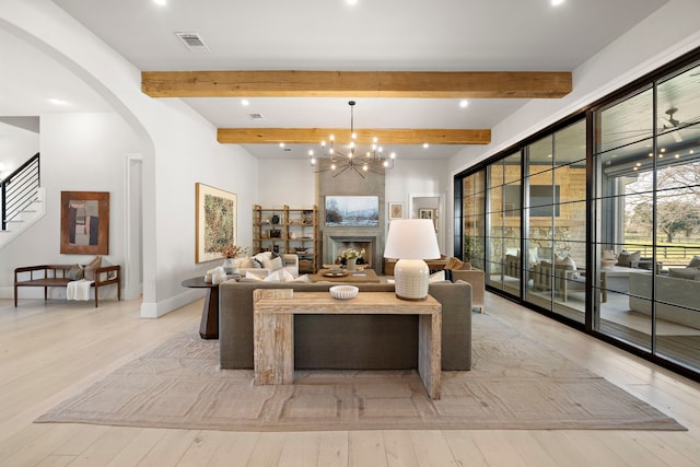 living room featuring light hardwood / wood-style floors, beam ceiling, a high end fireplace, and an inviting chandelier