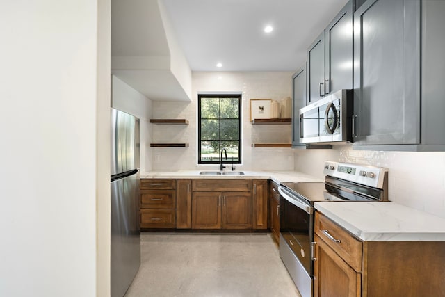 kitchen with sink, light stone countertops, appliances with stainless steel finishes, and tasteful backsplash