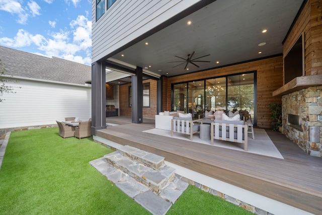 exterior space with ceiling fan, a deck, and an outdoor living space with a fireplace