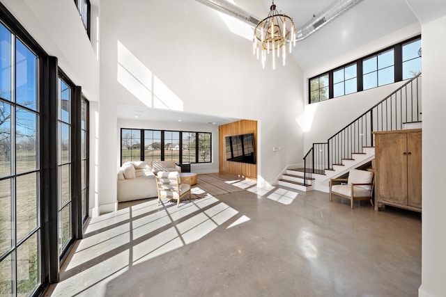 living room with a chandelier, concrete flooring, and a high ceiling