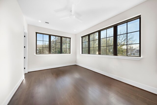 spare room featuring ceiling fan, a wealth of natural light, and dark hardwood / wood-style floors