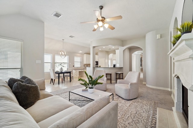 living room with ceiling fan with notable chandelier and a fireplace