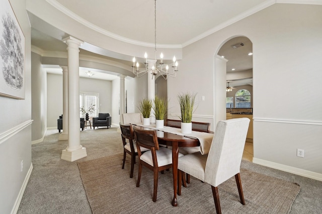 carpeted dining room with ornamental molding, a chandelier, and ornate columns