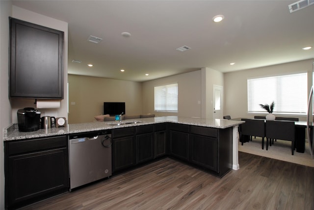 kitchen with sink, dark wood-type flooring, light stone counters, stainless steel dishwasher, and kitchen peninsula