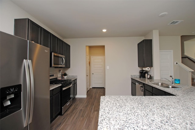 kitchen featuring light stone countertops, stainless steel appliances, dark wood-type flooring, and sink