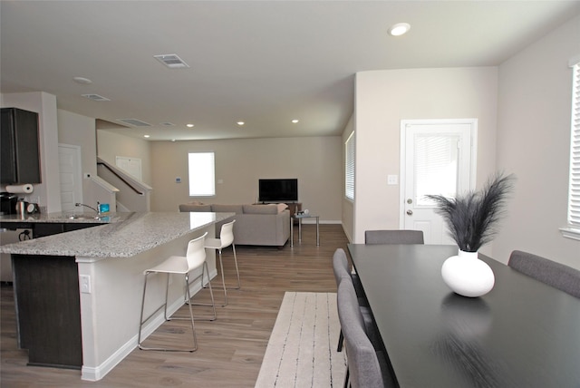 kitchen featuring light stone counters, sink, a center island, and light wood-type flooring