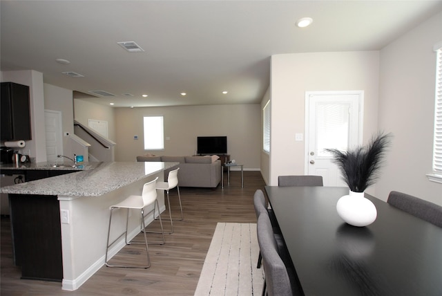 kitchen with sink, a center island, light stone counters, a breakfast bar area, and light wood-type flooring