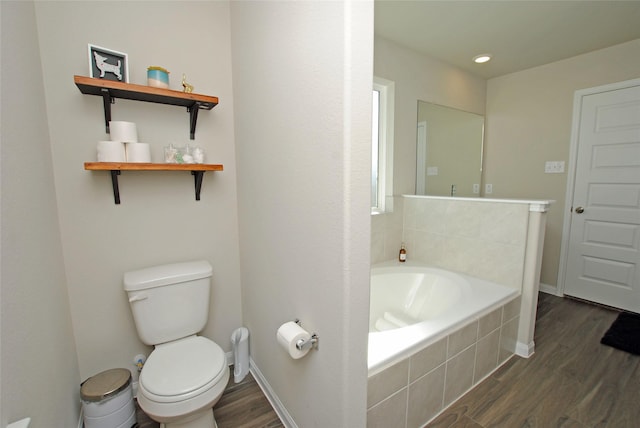 bathroom with tiled tub, wood-type flooring, and toilet