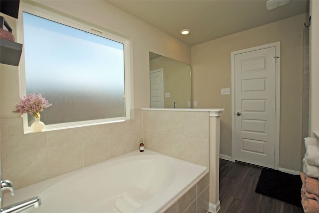 bathroom featuring tiled tub and wood-type flooring