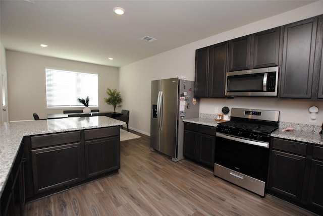 kitchen featuring light stone counters, wood-type flooring, and appliances with stainless steel finishes