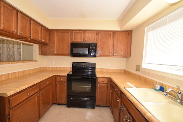 kitchen featuring black appliances, light tile patterned floors, and sink