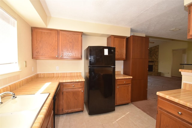 kitchen with sink, a textured ceiling, light tile patterned floors, and black appliances