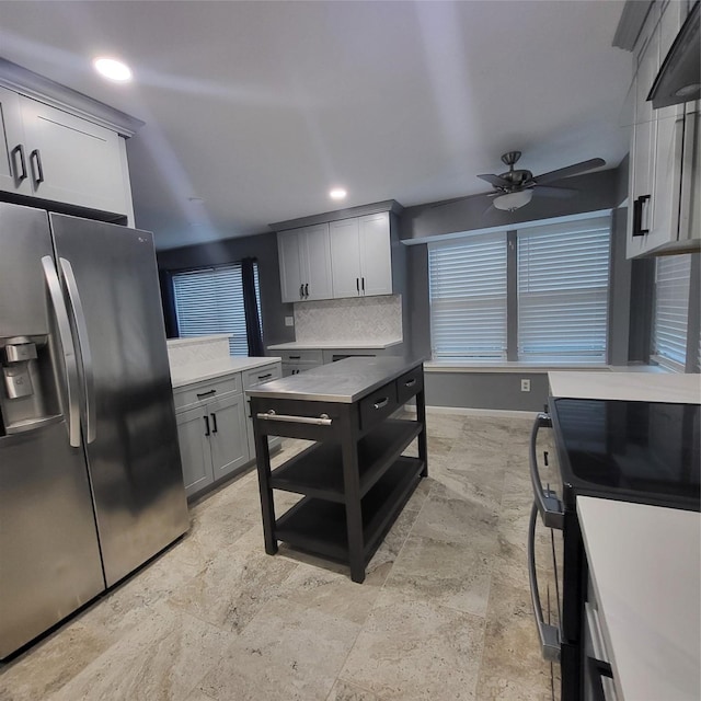 kitchen featuring black / electric stove, ceiling fan, gray cabinets, stainless steel fridge, and tasteful backsplash