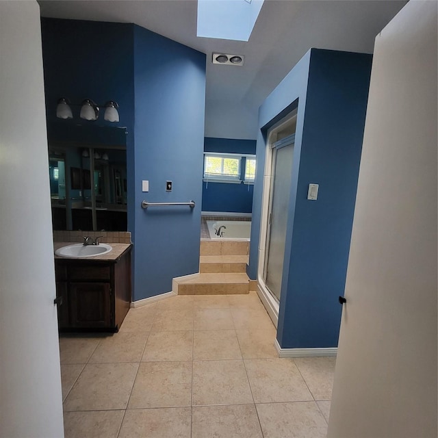 bathroom with tile patterned flooring, vanity, plus walk in shower, and a skylight