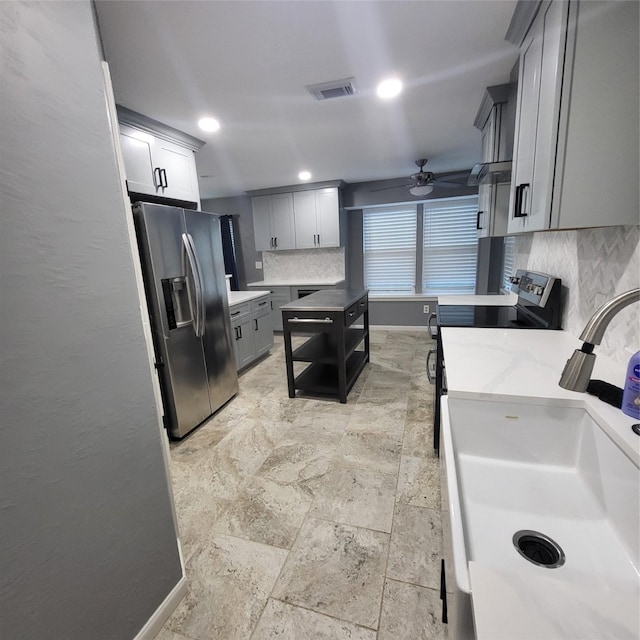 kitchen with ceiling fan, sink, stainless steel refrigerator with ice dispenser, stove, and gray cabinets