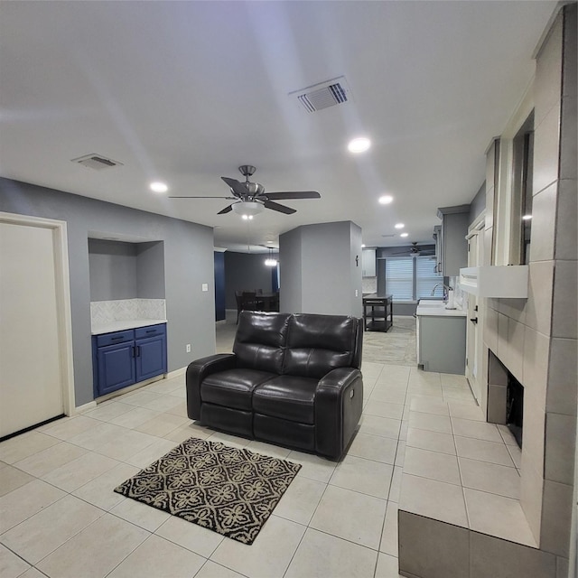 living room with a tile fireplace, ceiling fan, and light tile patterned flooring