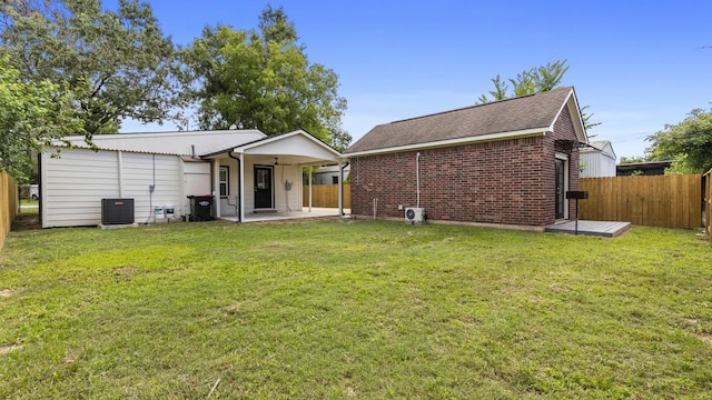 rear view of property with central AC unit, a patio area, and a yard