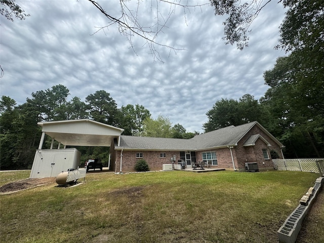 rear view of property featuring a lawn, a patio area, and central air condition unit