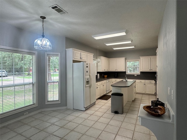 kitchen with pendant lighting, a center island, white refrigerator with ice dispenser, light tile patterned floors, and white cabinetry