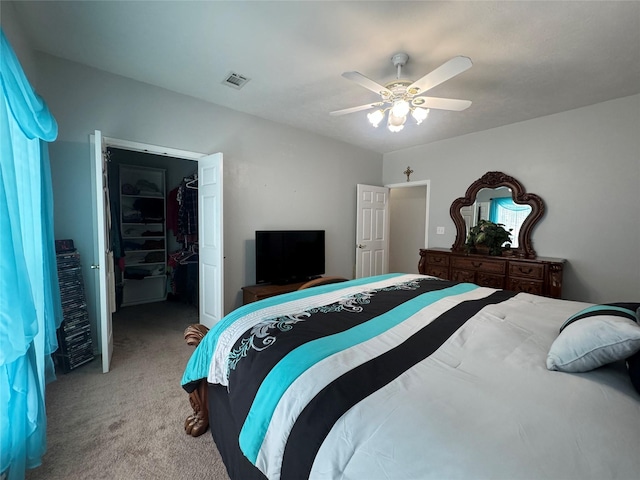 bedroom featuring light carpet, a closet, a spacious closet, and ceiling fan