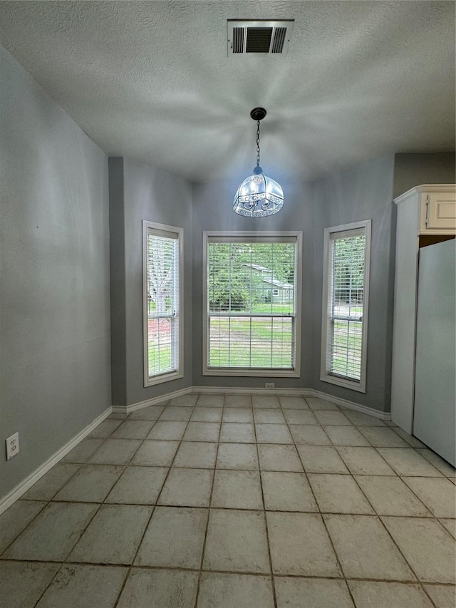 unfurnished dining area with light tile patterned floors and a chandelier