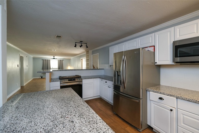 kitchen with crown molding, kitchen peninsula, appliances with stainless steel finishes, light stone counters, and white cabinetry