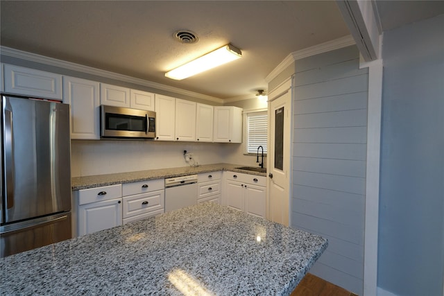 kitchen with light stone countertops, appliances with stainless steel finishes, white cabinetry, and sink