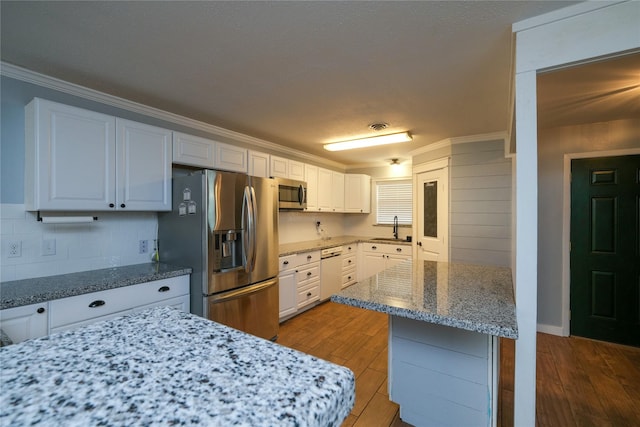 kitchen featuring sink, light hardwood / wood-style flooring, appliances with stainless steel finishes, light stone counters, and white cabinetry