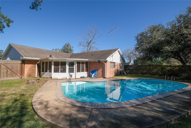 view of pool with a sunroom and a lawn