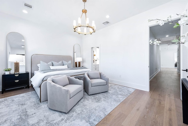 bedroom with wood-type flooring, ensuite bathroom, and a notable chandelier