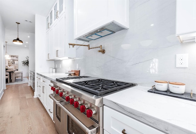 kitchen featuring ventilation hood, double oven range, white cabinetry, and light hardwood / wood-style flooring