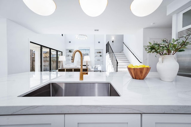 details with white cabinetry, light stone countertops, and sink