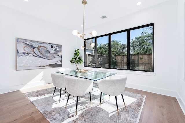 dining room with a wealth of natural light, wood-type flooring, and an inviting chandelier