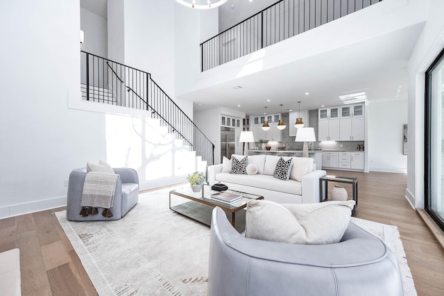 living room featuring a towering ceiling, light hardwood / wood-style flooring, and a wealth of natural light