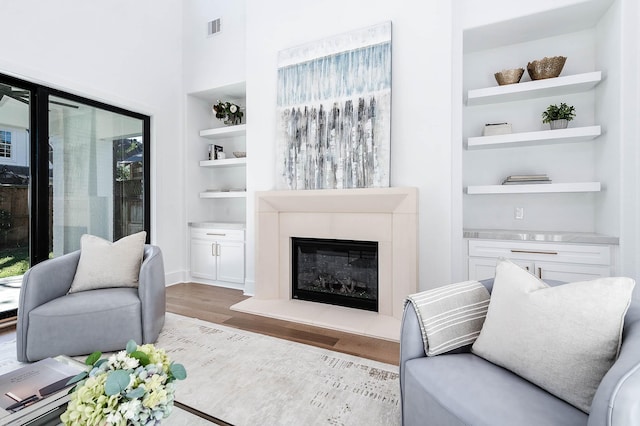 living room featuring built in shelves, light wood-type flooring, and plenty of natural light