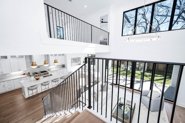 stairs with ceiling fan, a towering ceiling, and hardwood / wood-style flooring