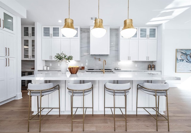 kitchen featuring backsplash, hanging light fixtures, and an island with sink