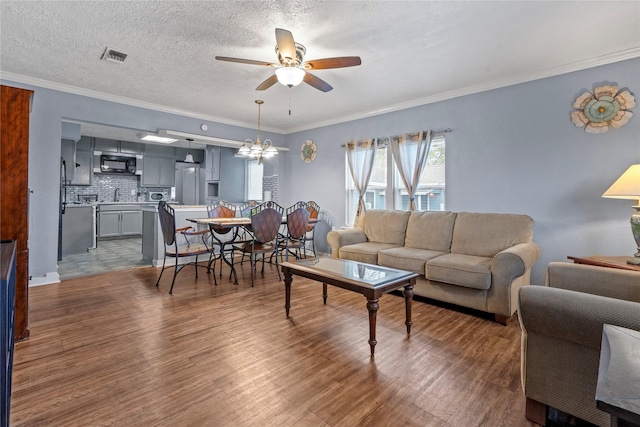 living room with a textured ceiling, dark wood-type flooring, ceiling fan, and ornamental molding