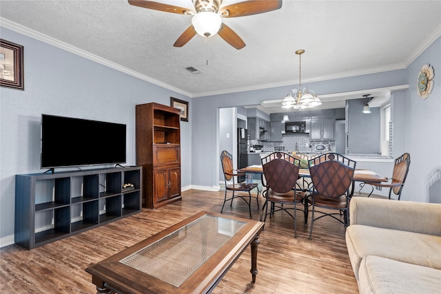 living room with crown molding, ceiling fan with notable chandelier, wood-type flooring, and a textured ceiling