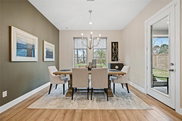 dining room featuring hardwood / wood-style floors, a healthy amount of sunlight, and a notable chandelier