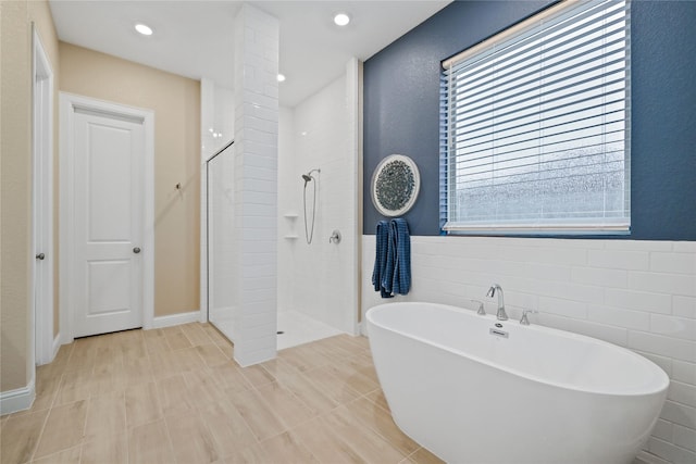 bathroom featuring tile walls and shower with separate bathtub