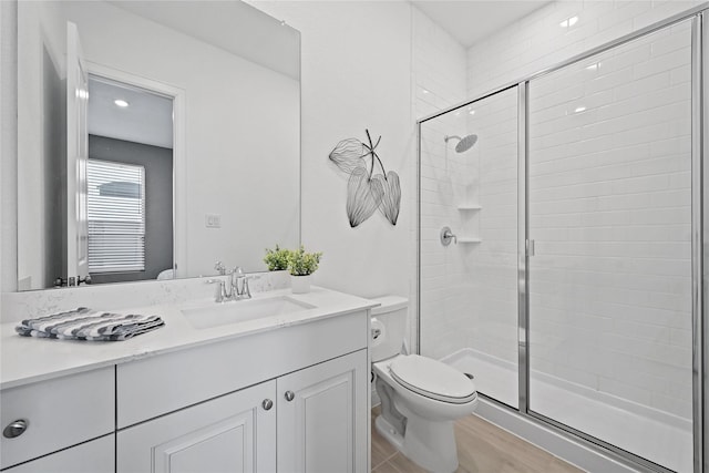 bathroom with hardwood / wood-style floors, vanity, toilet, and a shower with shower door