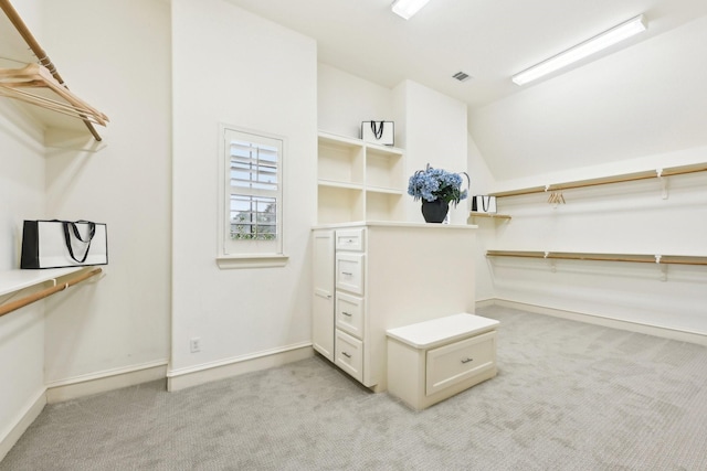 walk in closet featuring lofted ceiling and light carpet