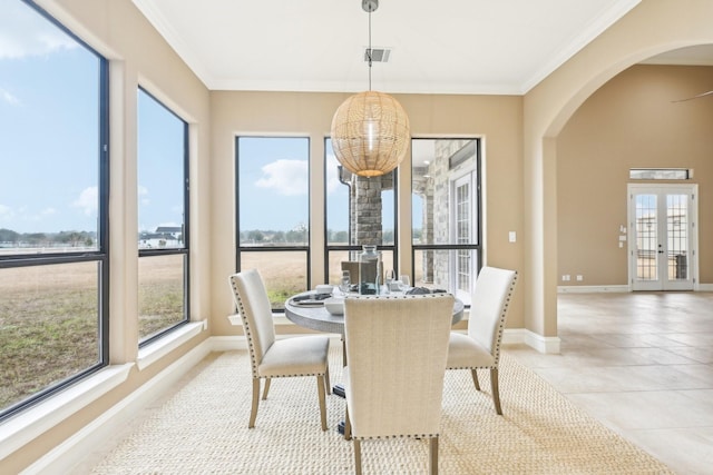 tiled dining area with crown molding and french doors