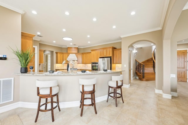 kitchen with light stone counters, a breakfast bar, appliances with stainless steel finishes, and kitchen peninsula